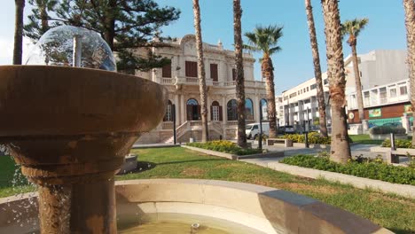 municipal university library of limassol overlooked by garden fountain - wide slide left to right reveal shot