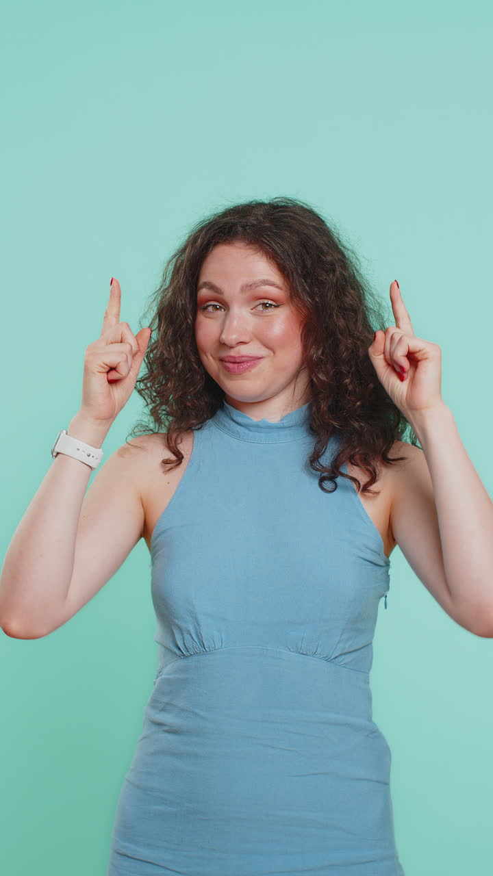 Young woman showing thumbs up and pointing overhead on blank space place for advertisement logo
