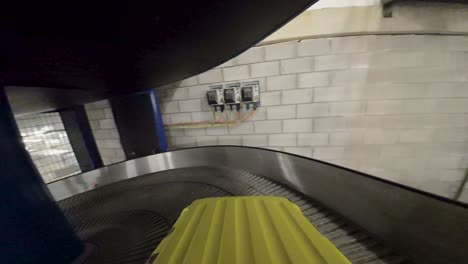 yellow suitcase on conveyor belt in airport baggage area, about to be loaded onto plane, industrial setting