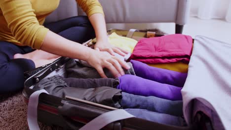 mujer joven terminando la preparación de ropa en maleta para viajar