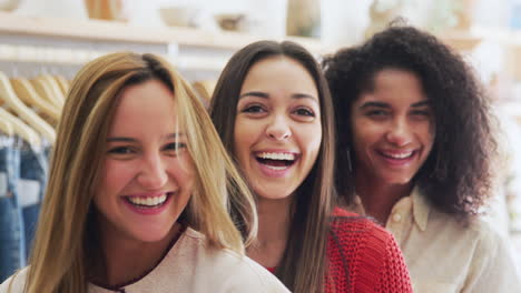 portrait of three female friends having fun shopping in clothes store together