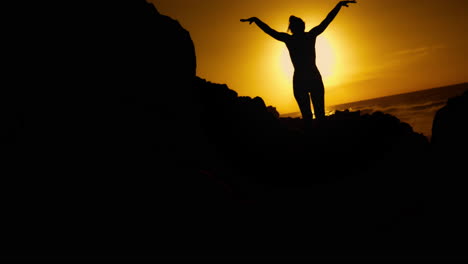 woman silhouetted at sunrise on rocks