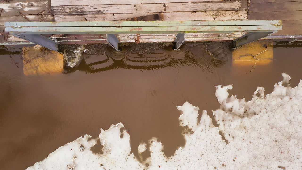 봄 에 녹는 얼음 홍수 물 이 호수 에 있는 배수관 을 따라 흐르고 있다. 공중 사진