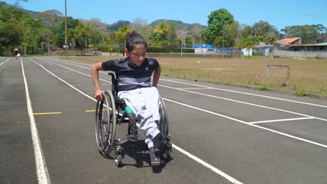 A-kid-with-disability-driving-a-wheelchair-on-a-track,-checking-with-himself-if-he-might-take-part-in-a-paracycling-race,-overcoming-his-fears