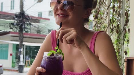 mujer disfrutando de una bebida púrpura al aire libre