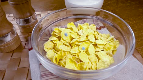 crispy yellow corn flakes into the bowl for the morning a delicious breakfast with milk. slow motion with rotation tracking shot.