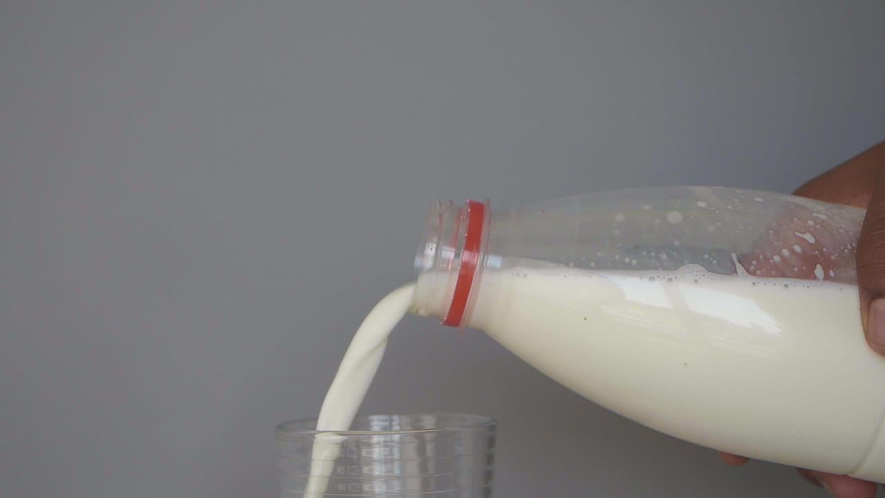 Milk being poured into a glass from a plastic bottle