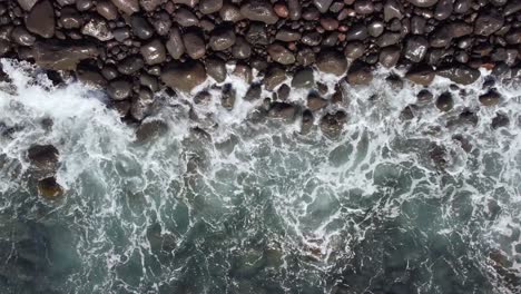 water waves splashing into pebble rocks at the seashore in canary island, tenerife, static