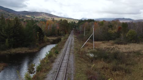 aerial flying low along train tracks beside androscoggin river