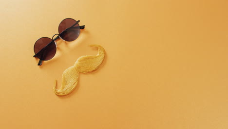 video de bigote falso rubio y gafas de sol redondas sobre fondo amarillo con espacio de copia