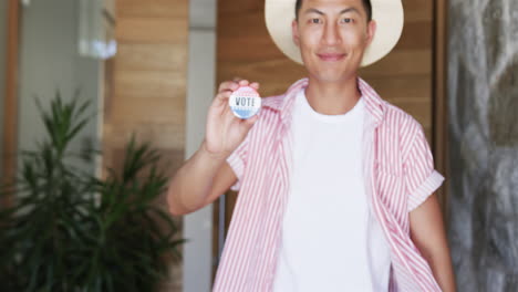 un joven asiático muestra una insignia de 'voto'