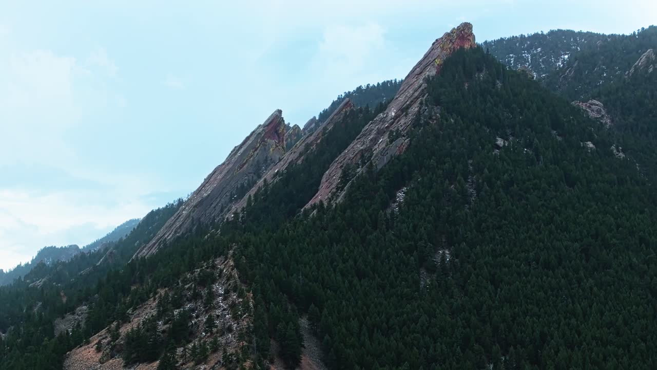 Aerial reveal of Boulder Flatirons’ majestic cliffs, blending rocky textures with forested areas