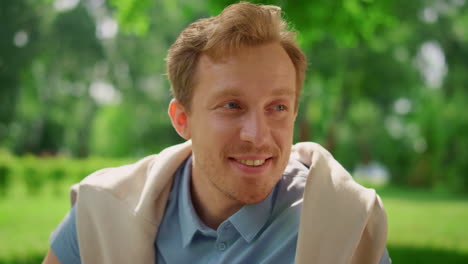 closeup smiling man on nature. portrait of handsome blond guy sitting on meadow.