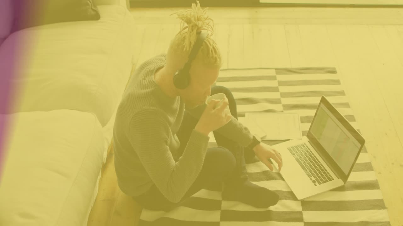 Remote worker pausing typing, sipping mug for break while rainbow overlay fading in tech hub