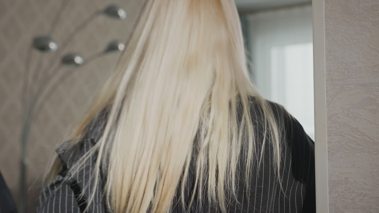 close up of woman with golden hair embracing companion while walking away indoors, focus on flowing strands against blurred background