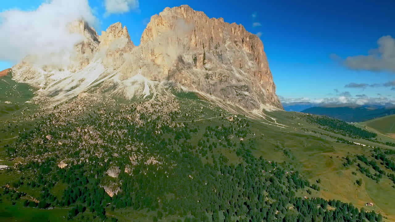 Cielo blu e nuvole bianche che si addensano sopra l'imponente gruppo del Sassolungo