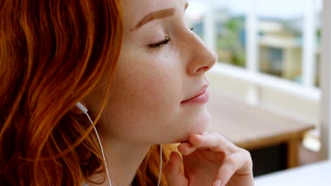 female graphic designer listening music on headphones in office 4k