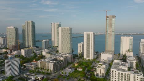 forwards fly above urban borough. row of modern tall residential buildings on waterfront lit by bright sunshine. miami, usa