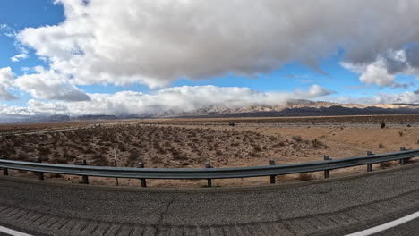 conduciendo a través del terreno accidentado del desierto de mojave en una carretera como se ve desde la ventana del pasajero