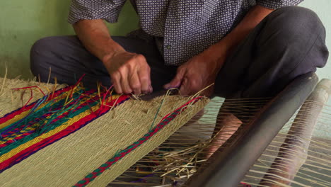 colchón colorido hecho a mano. hombre cortando fibras de alfombra