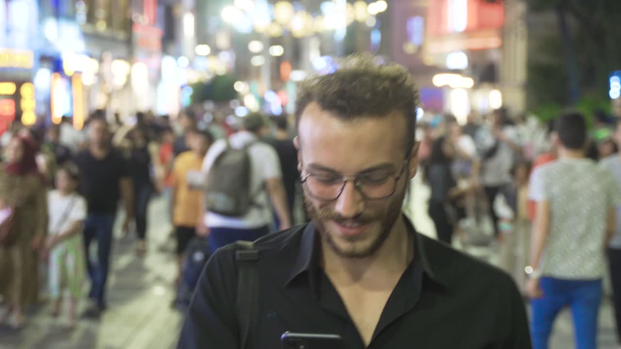 joven usando el teléfono en la multitud nocturna.