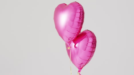 video de dos globos rosados brillantes en forma de corazón flotando sobre un fondo blanco, con espacio para copiar.