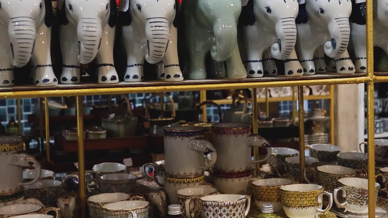 A collection of elephant figurines and intricately designed ceramic cups made in Thailand.