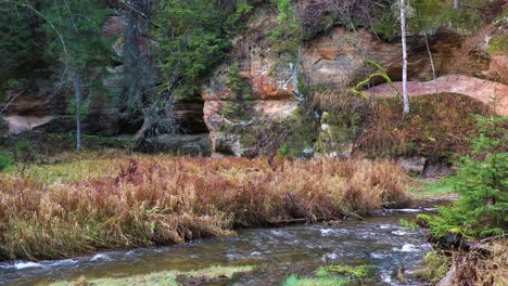 natural formed rocky cliff with cave and river nearby, aerial view