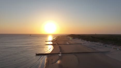 aerial view of breakwater poles on the beach during sunset in zoutelande, westkapelle, netherlands