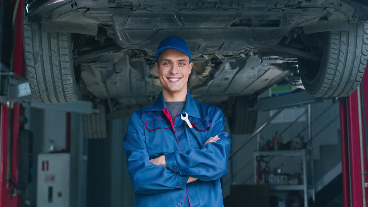 mecánico confiado posando delante de un coche subido