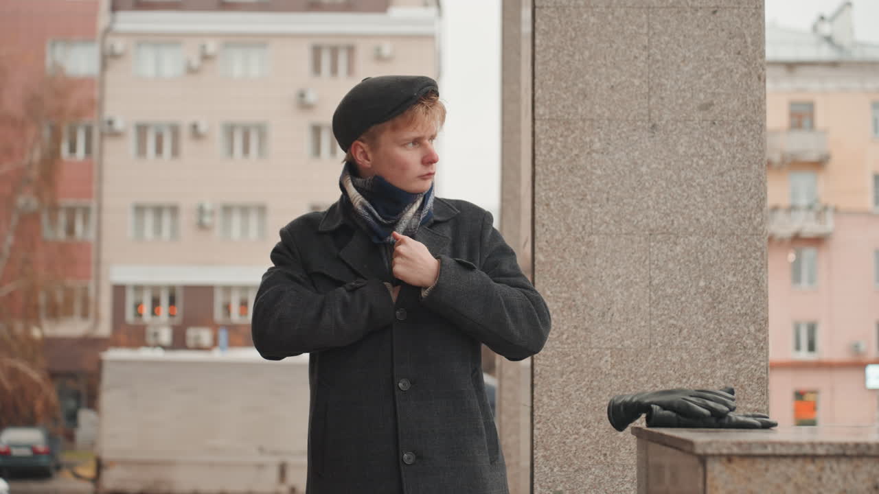 Artist gazes thoughtfully. Creator surveys cityscape calmly. Artistic individual studies skyline with intent. Fashionable figure beside column contemplates urban environment carefully