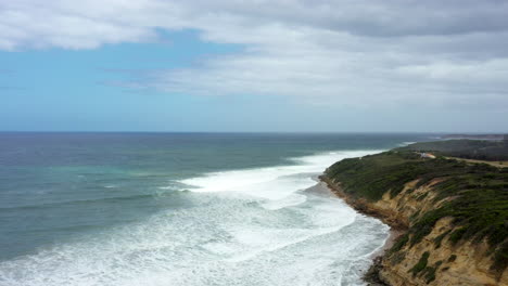 AERIAL-White-Waves-Roll-Into-The-Coastline-Of-Bells-Beach,-Australia