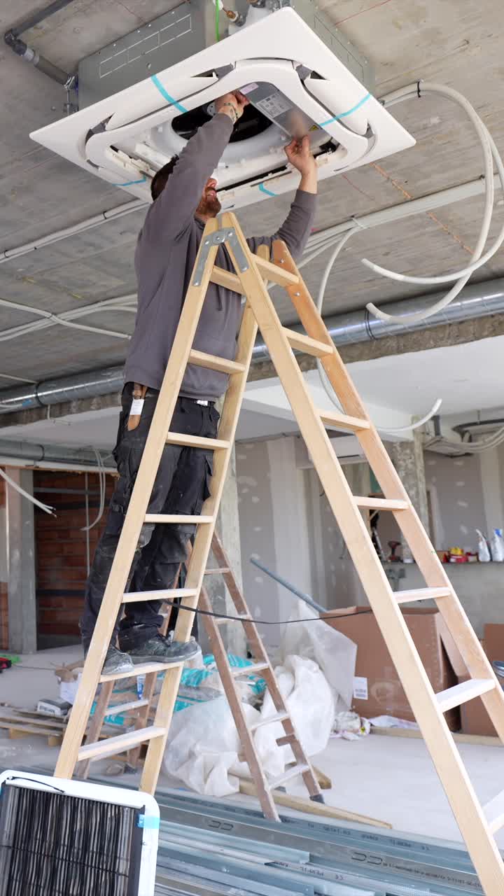 Man Installing Air Conditioning Unit on Ceiling at Construction Site