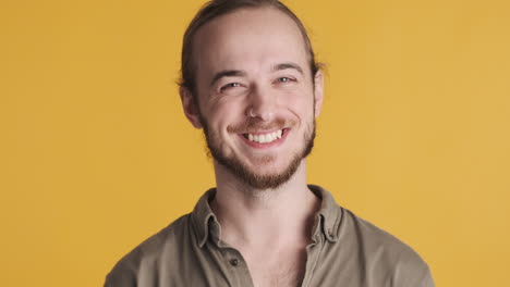 un joven caucásico asintiendo con la cabeza y sonriendo a la cámara.
