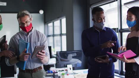 Office-colleagues-wearing-face-masks-discussing-with-each-other-at-modern-office