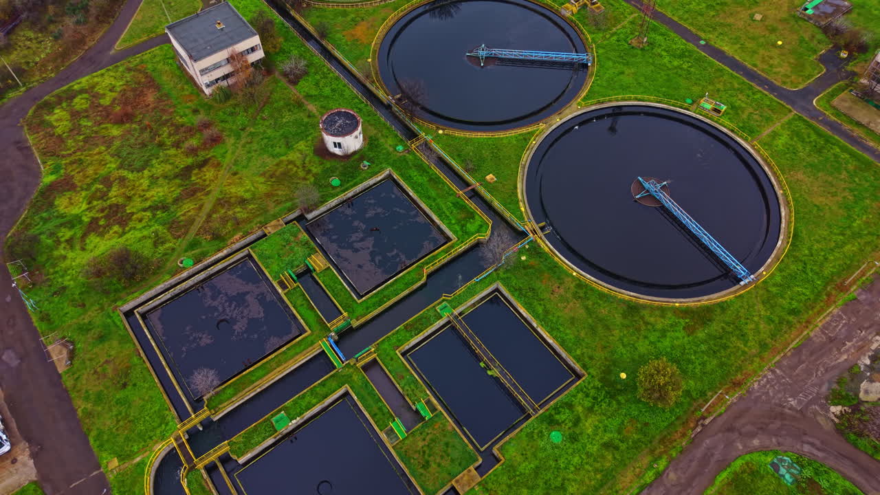 Water treatment facility shows tanks and management area in a rural setting during daytime with clear skies and green surroundings