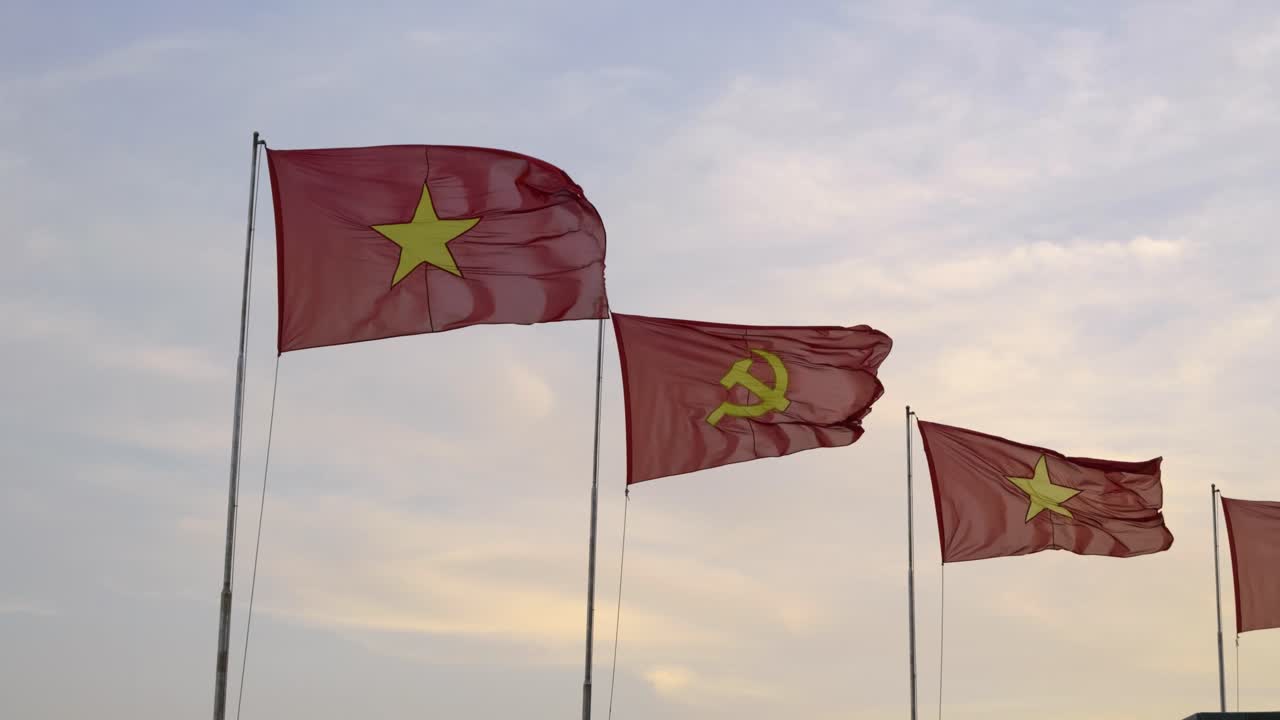 Vietnamese and communist flag waving in slow motion against cloudy sky
