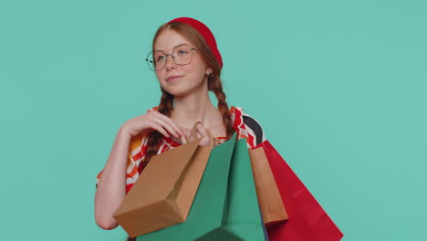 chica pelirroja mostrando bolsas de compras, anuncios de descuentos, sonriendo mirando asombrado con los precios bajos