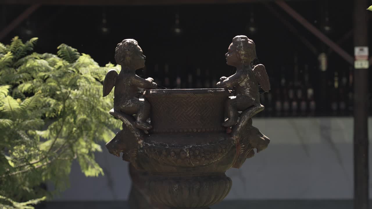 decorative bronze fountain with cherub figures in warm outdoor setting