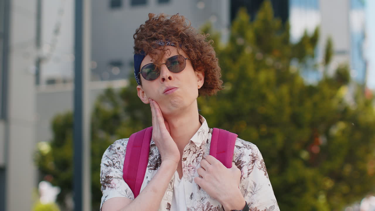 Man tourist suffering from toothache feels pain holds his hand near his cheek on city street