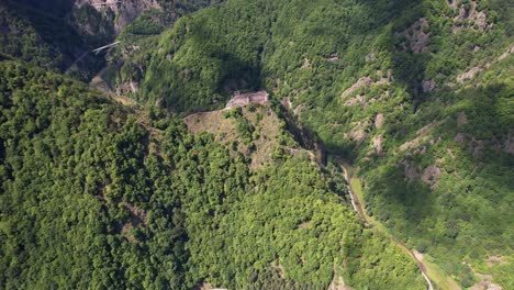 Ruinas-De-La-Ciudadela-De-Poenari-Con-La-Presa-Vidraru-En-Primer-Plano,-Rodeada-Por-Las-Majestuosas-Montañas-Fagaras,-Bajo-Un-Cielo-Despejado