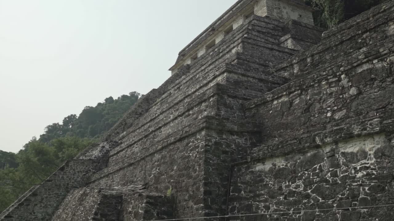 A slow-motion clip capturing the weathered grandeur and imposing scale of one of Palenque's primary stepped pyramids, the Temple of the Inscriptions