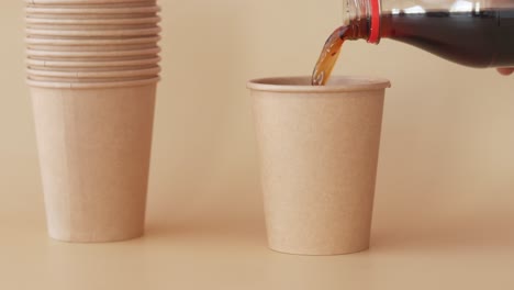 pouring soda into a stack of eco-friendly paper cups