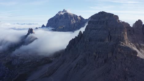 cloud inversion in valleys of majestic italian alps - drone flight among rugged mountain peaks, sexten dolomites