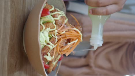 bowl of salad with dressing being added