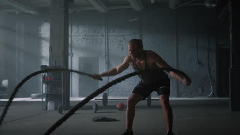 bodybuilder working with battle ropes. athletic man practicing fitness exercise