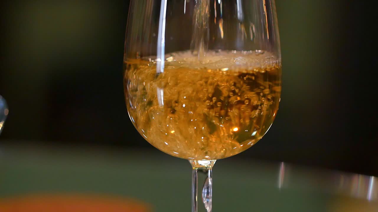 Bicchiere che si riempie di vino bianco.
