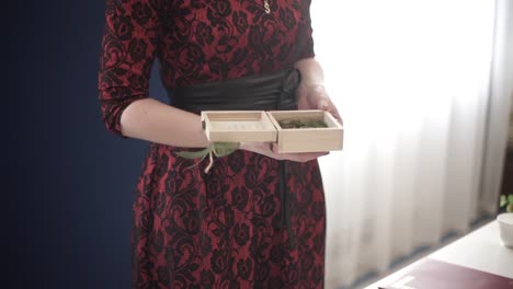 woman holding a wooden ring box in a red dress