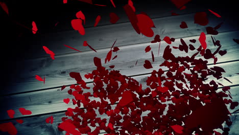 red hearts falling on wooden surface