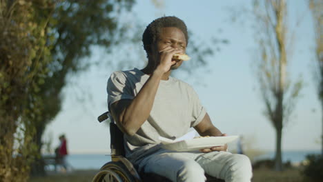 low angle shot of young man in wheelchairt enjoying his snack